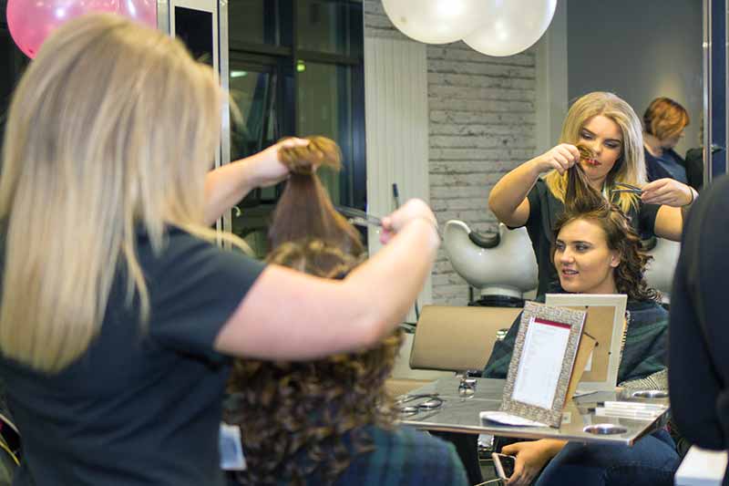 A womans hair being cut by a student.